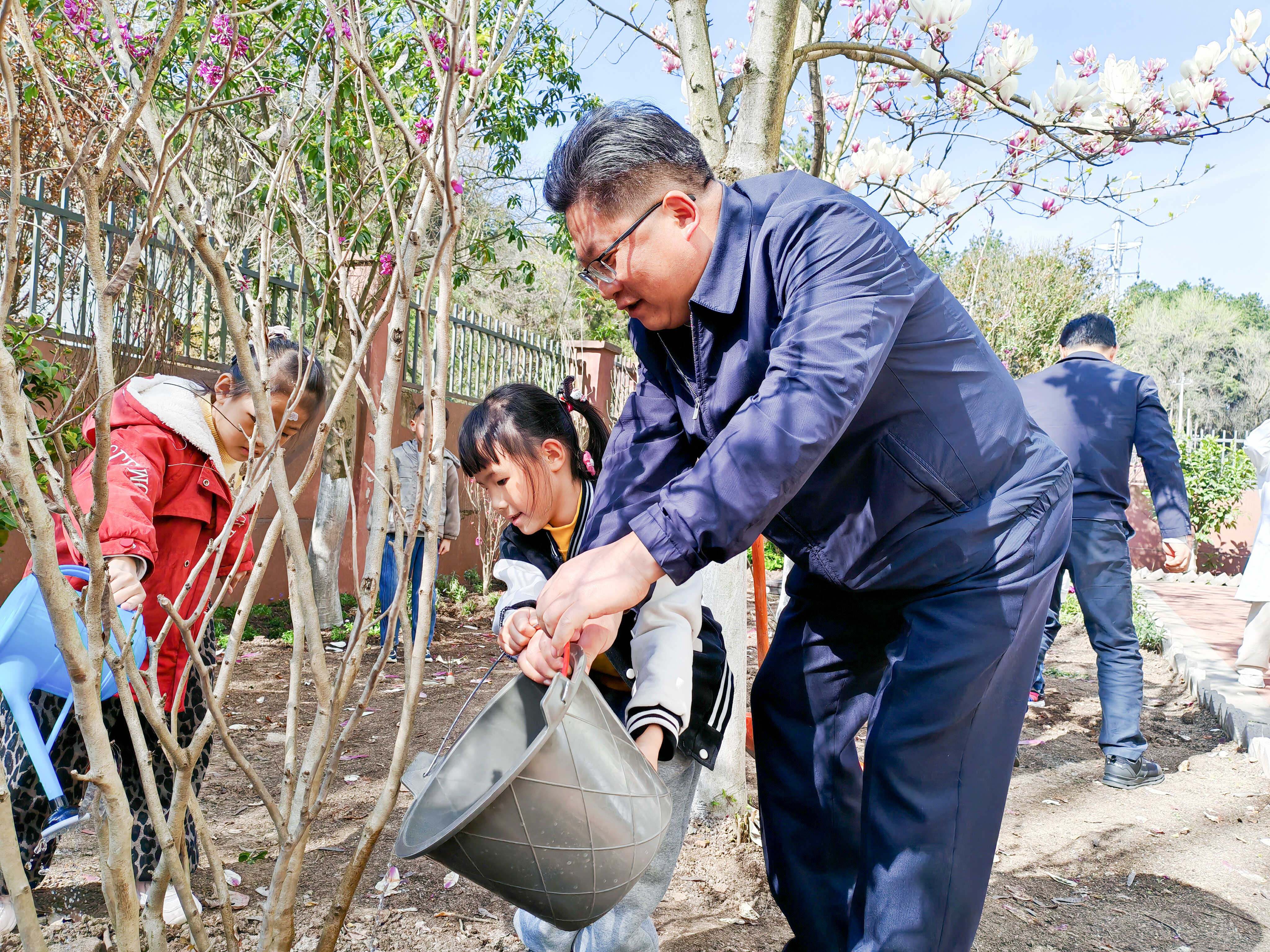 图为周代军与儿童共同浇灌树木